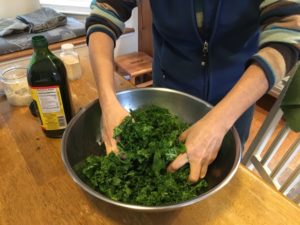 Coating kale chips with olive oil and spices.
