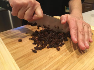 Chopping raisins with a rocking motion.