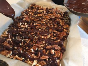 Using spoon to drizzle melted chocolate for Pecan Bark